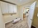 Laundry room with overhead cabinets, sleek flooring, and convenient access to the adjacent kitchen at 93 Mill Creek Rd, Hiram, GA 30141