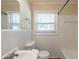 The bathroom features a white tiled wall, vanity with sink, commode, bathtub, and window at 158 Polar Rock Sw Dr, Atlanta, GA 30315