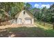 Detached garage with an upper level and surrounded by mature trees with fencing around the property at 1240 Evans Cook Rd, Canton, GA 30115