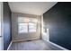 Bedroom with hard surface flooring, dark gray accent wall, window with damaged blind, and closet at 546 W Sherwood Dr, Riverdale, GA 30274