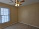 An empty bedroom featuring tile floors, a ceiling fan, and a window with blinds for ample natural light at 634 S Jeff Davis S Dr, Fayetteville, GA 30215