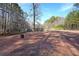 Expansive brick backyard area with a metal ladder and a wooden bench, surrounded by tall trees at 210 Cowan Se Rd, Conyers, GA 30094
