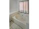 Soaking tub area with tiled floors and privacy window at 210 Cowan Se Rd, Conyers, GA 30094