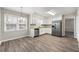 Open kitchen with stainless steel appliances, granite counters, white cabinets, and wood-look flooring at 1876 Winding Creek Sw Ln, Marietta, GA 30064