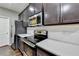 Modern kitchen with stainless steel appliances, dark wood cabinets, and white subway tile backsplash at 5264 Mill Way, Stone Mountain, GA 30083