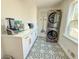 Bright laundry room featuring stacked washer and dryer, stylish patterned tile floor, and counter space with modern appliances at 152 Weatherstone Pkwy, Marietta, GA 30068