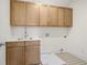 Functional laundry room with wood cabinets, sink, and patterned tile flooring at 2517 Canopy Ct, Marietta, GA 30066