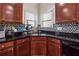 Close-up of a kitchen sink with mosaic tile backsplash, dark granite countertops, and wooden cabinets at 5955 Princeton Run Trl, Tucker, GA 30084