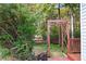 Landscaped backyard with a wooden arbor next to the exterior of a home at 1421 Eryn Cir, Suwanee, GA 30024