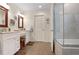 Bright bathroom with double vanity, wood-look tile floors, and glass-enclosed tub and shower at 1421 Eryn Cir, Suwanee, GA 30024