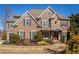 Stunning two-story brick home featuring a stone facade, wood accents, and meticulously landscaped front yard at 5650 Copper Creek Pass, Cumming, GA 30040