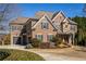 Two-story brick home boasts a stone accent, an attached garage, and a circular driveway surrounded by lush landscaping at 5650 Copper Creek Pass, Cumming, GA 30040