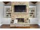 Stone fireplace featuring built-in shelves, décor, and large television at 5650 Copper Creek Pass, Cumming, GA 30040