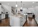 Modern kitchen with a large island, sleek white cabinetry, stainless steel appliances, and an adjacent living area at 3908 Charleston Market St, Suwanee, GA 30024