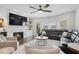 Inviting living room featuring a stone fireplace, a large black leather sofa, and a ceiling fan at 3908 Charleston Market St, Suwanee, GA 30024