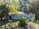 Back of house featuring three windows and a door, surrounded by mature trees and natural landscaping at 724 Se Cowan Se Rd, Conyers, GA 30094