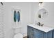 Modern bathroom featuring a blue vanity with gold hardware, round mirror and a white toilet at 2550 Belaire Dr, Cumming, GA 30041