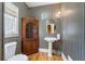 Stylish half-bathroom with pedestal sink, decorative mirror, and wallpapered accent wall at 4610 Riversound Drive, Snellville, GA 30039