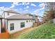 Backyard view of modern homes with a sloped lawn and wooden fencing at 118 Village Green Ave, Woodstock, GA 30189