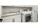 Bright laundry room features a granite countertop, sink, washer and dryer, and white cabinetry at 118 Village Green Ave, Woodstock, GA 30189