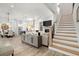 Bright, open-concept living room featuring modern decor, a staircase, and seamless flow to the dining and kitchen areas at 118 Village Green Ave, Woodstock, GA 30189