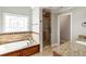 Elegant bathroom features a soaking tub under decorative window and a glass enclosed shower at 2190 Rugby Ave, Atlanta, GA 30337