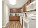 Well-lit kitchen with wood cabinets, white appliances, granite countertops, and wood-look flooring at 3653 Memorial Nw Pkwy, Kennesaw, GA 30152