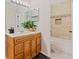 Well-lit bathroom featuring light wood cabinets, stylish fixtures, and tiled shower/tub combo with decorative mosaic border at 4106 Pine Heights Ne Dr, Atlanta, GA 30324