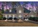 Beautifully lit home at dusk featuring a stone facade, arched windows, mature trees and manicured lawn at 4990 Sawgrass Nw Pl, Acworth, GA 30102