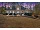 Beautifully lit home at dusk featuring a stone facade, arched windows, mature trees and manicured lawn at 4990 Sawgrass Nw Pl, Acworth, GA 30102