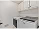 Well-lit laundry room equipped with a washer, dryer, and overhead storage cabinets at 4990 Sawgrass Nw Pl, Acworth, GA 30102