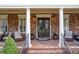 Inviting front porch with brick flooring, comfortable seating, and decorative front door with wrought iron details at 8025 Georgetown Cir, Suwanee, GA 30024