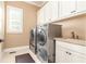 Bright laundry room with side-by-side washer and dryer and storage cabinets at 8025 Georgetown Cir, Suwanee, GA 30024