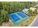 Aerial view of blue community tennis courts with adjacent pool and trees at 8025 Georgetown Cir, Suwanee, GA 30024