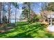 Lush backyard featuring a well-kept lawn, mature trees, and beautiful lake views at 6475 Holland Dr, Cumming, GA 30041