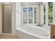 Bathroom featuring a soaking tub, a separate shower and a large window that provides plenty of natural light at 6475 Holland Dr, Cumming, GA 30041