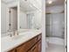 Bright bathroom featuring a shower over tub, wood vanity, and a large mirrored wall at 6475 Holland Dr, Cumming, GA 30041