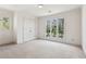 Bright bedroom featuring neutral carpet, white walls, large windows, and a double door closet at 6475 Holland Dr, Cumming, GA 30041