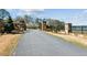 Long driveway leading to a gated stone entrance, with manicured landscaping and partial view of the lake at 6475 Holland Dr, Cumming, GA 30041