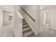 Carpeted staircase with neutral walls, a wood handrail, natural lighting, and access to a hallway and doorway at 1084 Georgian Point Dr, Lawrenceville, GA 30045