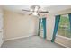 A bedroom features two windows, teal colored curtains, neutral carpet and a ceiling fan with light at 12947 Dunand Blvd, Hampton, GA 30228