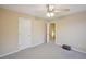 Neutral carpeted bedroom features a ceiling fan and leads to a staircase, offering a simple and comfortable space at 12947 Dunand Blvd, Hampton, GA 30228