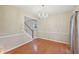 An empty dining room boasts hardwood floors, neutral paint, chandelier, and bright natural light at 12947 Dunand Blvd, Hampton, GA 30228