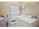 Bright laundry room featuring a white washer, dryer, shelving, and a window for natural light at 12947 Dunand Blvd, Hampton, GA 30228