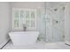 Bright bathroom featuring a stand alone tub and glass enclosed shower with luxury gold details at 8900 River Trace Dr, Johns Creek, GA 30097