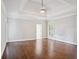 Spacious bedroom with hard wood floors, a tray ceiling and a door leading to an ensuite bathroom at 8900 River Trace Dr, Johns Creek, GA 30097