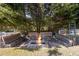Cozy outdoor fire pit with built-in seating, nestled among mature trees and a peaceful setting at 2316 Watson Fain Trl, Loganville, GA 30052