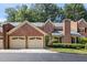 Attractive brick townhome with a two-car garage, front lawn, mature trees, and classic brick chimney at 52 Ivy Chase Ne, Atlanta, GA 30342