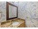 Charming powder room with a granite countertop, decorative mirror, and unique wallpaper with intricate detailing at 52 Ivy Chase Ne, Atlanta, GA 30342