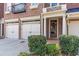 Close up of brick townhome garages, front door with wreath, and manicured landscaping at 7524 Portbury Park Ln, Suwanee, GA 30024